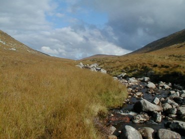 Irish uplands showing a rocky stream flowing down a grassy hill
